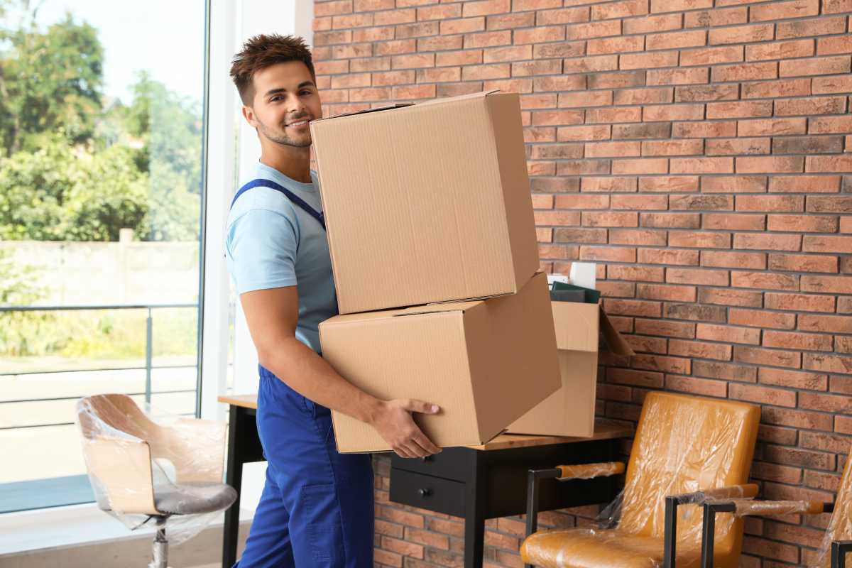 Young worker carrying cardboard boxes in office.