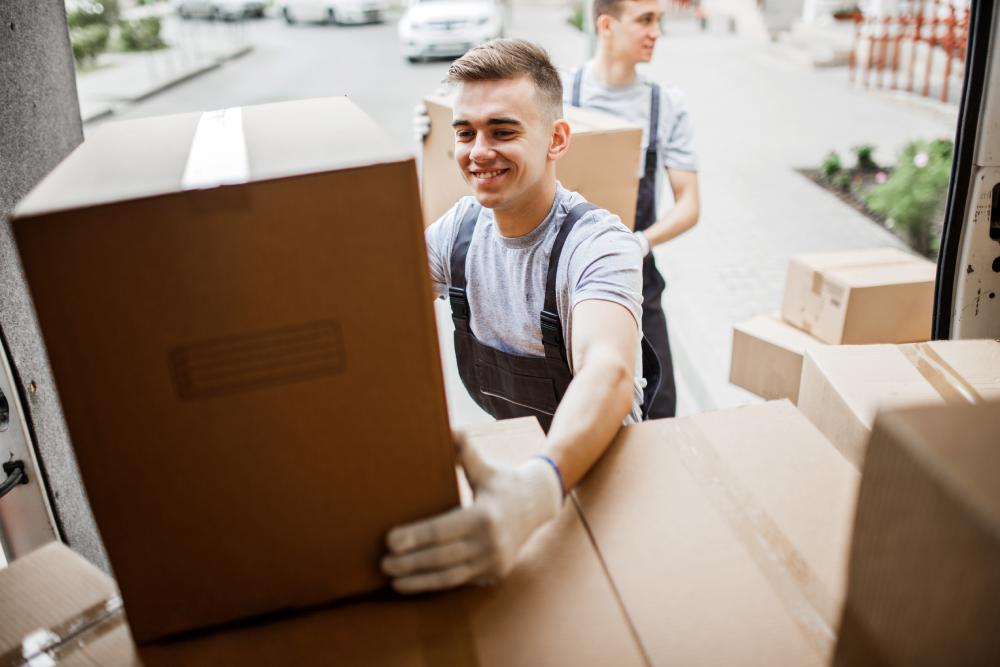 Employees Of A Specialty Moving Company Picking Up Boxes Off Truck