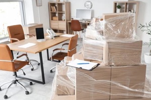 wrapped cardboard boxes with stretch film and clipboard in office on moving day