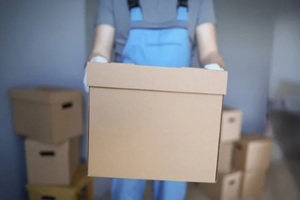 close-up of worker loading cardboard boxes with owners belongings to new apartment