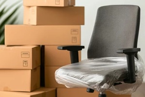 close up of office chair wrapped in plastic, surrounded by stacked cardboard boxes