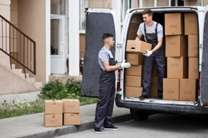 two young handsome movers wearing uniforms are unloading the van