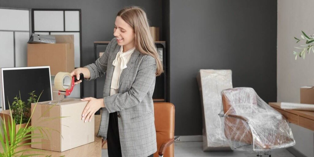 young businesswoman taping box in office on moving day