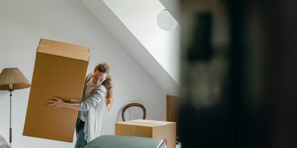 woman carrying boxes in new apartment