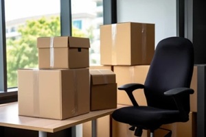 stack of cardboard boxes with stuff and office chair in empty office room