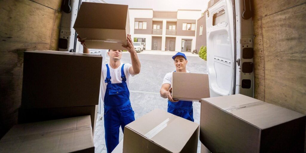 two removal company workers unloading boxes from minibus