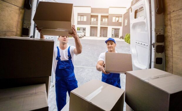 two removal company workers unloading boxes from minibus