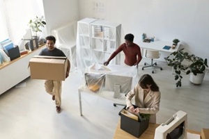 Employees packing furniture and boxes during an office move.