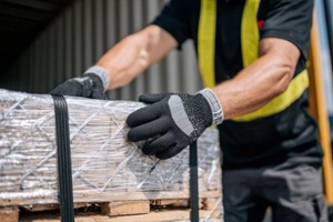 close-up of hands wearing gloves securing cargo straps on freight pallet inside transport truck