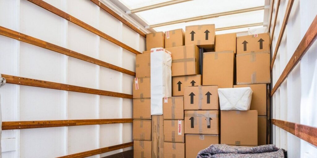 inside of a removal van, showing fabric blankets stacked and a background of cardboard boxes - climate-controlled storage for businesses