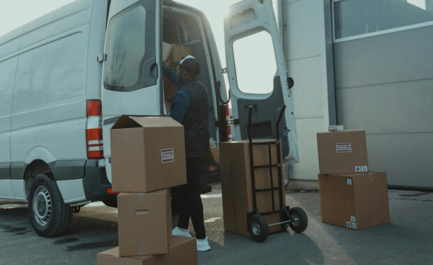 courier loading cardboard boxes into a delivery van outside a warehouse - GSA certified movers
