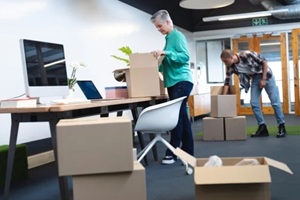 male and female executives unpacking cardboard boxes in office